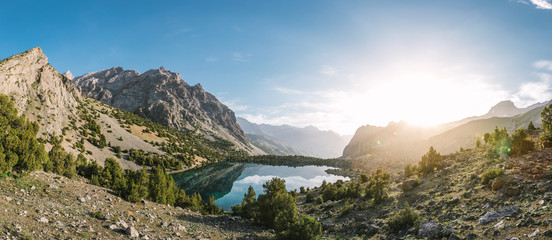 panoramashot of beautiful mountain lake in the mountainside of tajikistan at sunrise - alaudin lake