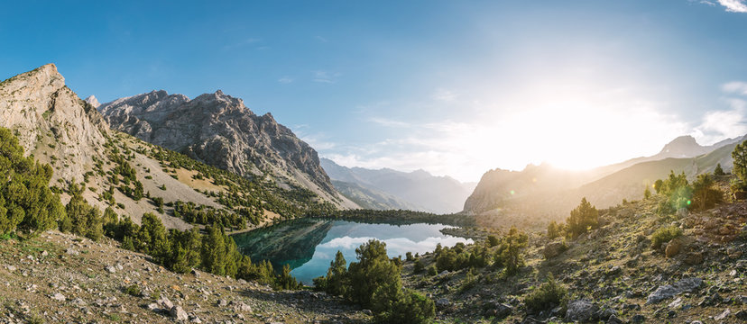 panoramashot of beautiful mountain lake in the mountainside of tajikistan at sunrise - alaudin lake