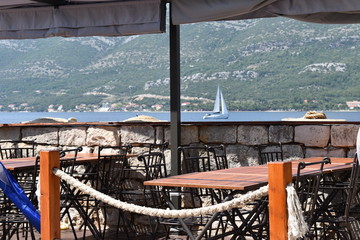 Sea viewing restaurant on the Korcula town promenade and a catamaran background, Korcula island, Croatia
