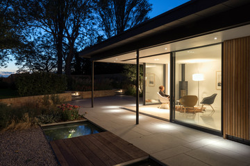 External picture of large glass doors of a garden room at night.