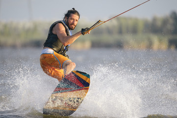 Full-length portrait of caucasain man wakeboarding on the lake