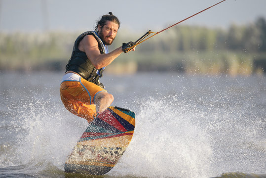 Full-length portrait of caucasain man wakeboarding on the lake