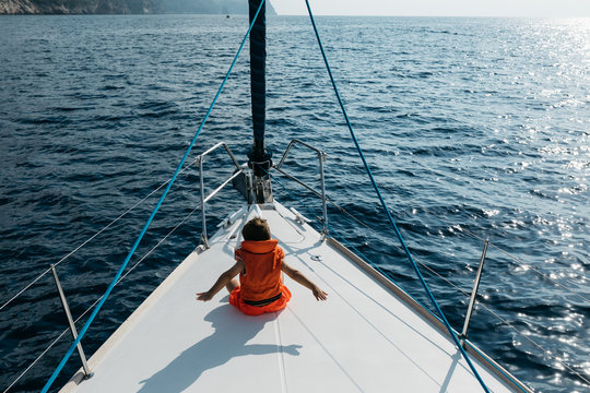 Kid enjoying summer on bow of yacht.