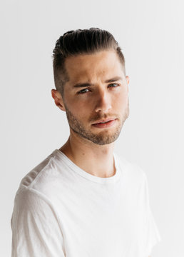 Head shot portrait of young adult male with short hair wearing white t-shirt in studio
