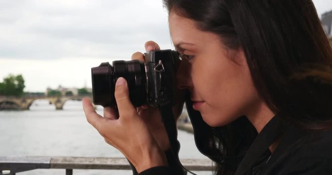 Side view of millennial woman on bridge over the Seine taking photo with dslr camera, Young travel photographer focuses lens and takes picture while on vacation in Paris, 4k