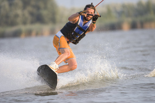 Handsome caucasian man riding wakeboard on the lake