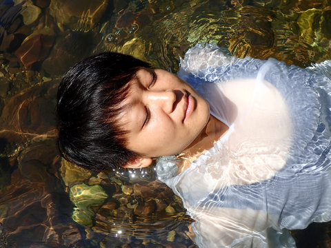 Bare upper body of the woman, lying down into the water