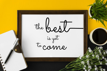 Wood frame with motivational and inspirational wisdom quote on yellow and black background. The best is yet to come.