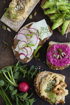 Open face vegetarian sandwiches on a wooden board.