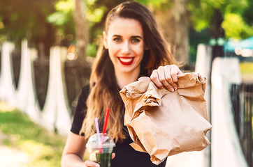 the girl is holding the package with the purchase. smile on his face. cocktail with ice, mint, lime, lemon, topping. refreshing drink glass. beautiful girl. Street style