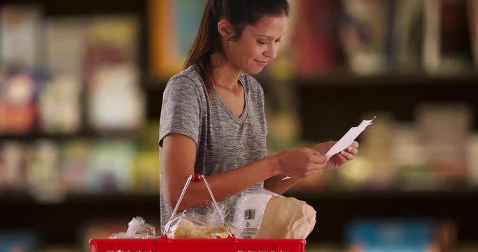 Portrait of young wife or mother with shopping list at the grocery store, Pretty Caucasian woman checking food items in her basket, 4k