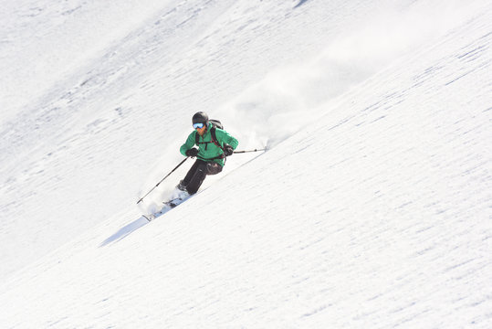 Male skier freeriding downhill steep snow-capped slope
