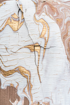 White and gold liquid paint on cracked surface