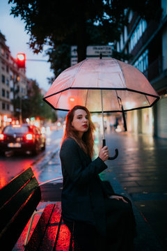 woman with a trasparent umbrella on a rainy ay with the city lights