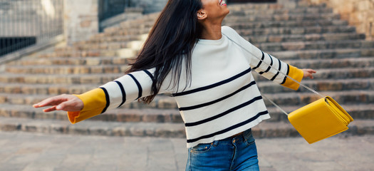 Happy stylish woman dancing on the street.