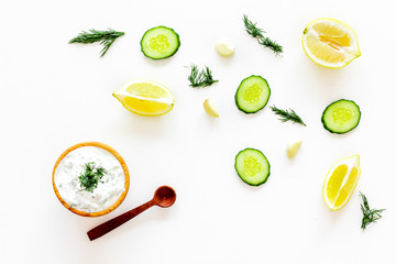 Greek yogurt dip with greenery, cucumber, oranges, garlic on white background top view pattern