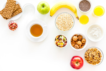 Ingredients for healthy breakfast. Fruits, oatmeal, yogurt, nuts, crispbreads, chia on white background top view copy space