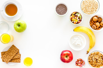 Ingredients for healthy breakfast. Fruits, oatmeal, yogurt, nuts, crispbreads, chia on white background top view copy space