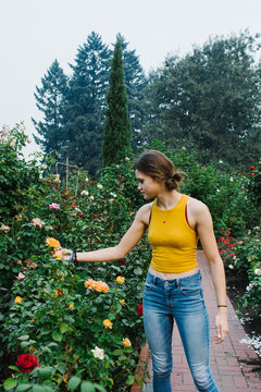 teen looking at roses in rose garden