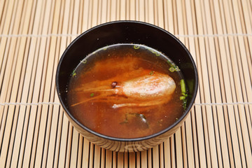 Miso soup with shrimp in bowl on bamboo background