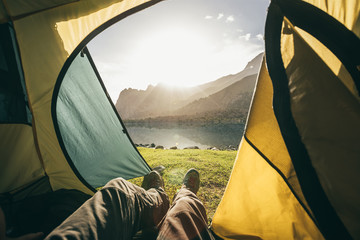 view out of a tent to a mountain lake at sunrise