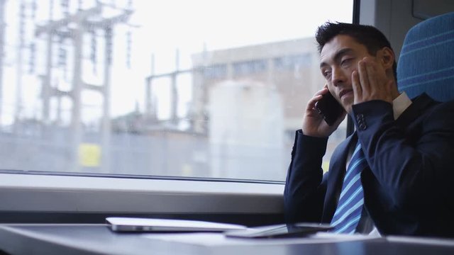 Tired asian business man on a phone call during a train journey