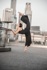 Beautiful Young Girl Dancing in the City, wearing black, with background of skyscrapers 
