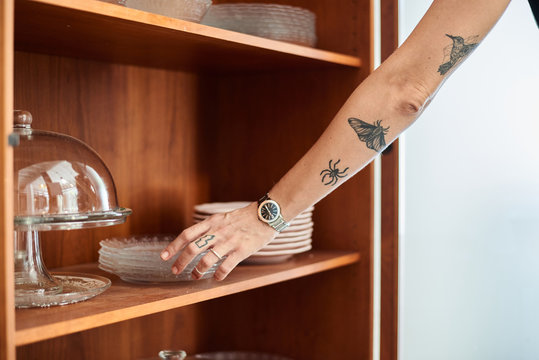 Waitress taking glass plates from shelf.