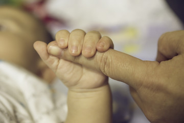 The hands of the mother  hold the baby's hand with love and caring.