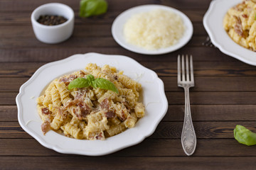 Homemade Pasta carbonara Italian with Bacon, eggs, Parmesan Cheese on white plate on a dark background.