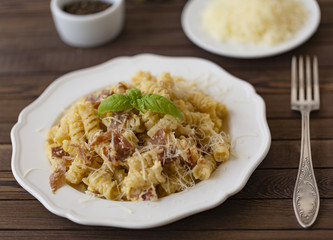 Homemade Pasta carbonara Italian with Bacon, eggs, Parmesan Cheese on white plate on a dark background.
