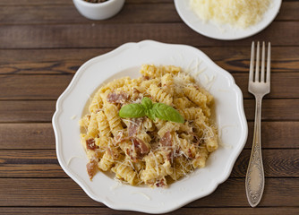 Homemade Pasta carbonara Italian with Bacon, eggs, Parmesan Cheese on white plate on a dark background.