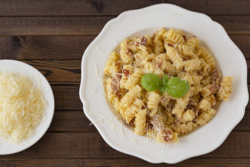 Homemade Pasta carbonara Italian with Bacon, eggs, Parmesan Cheese on white plate on a dark background.