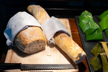 French baguette and bread wrapped in cloth on wooden board