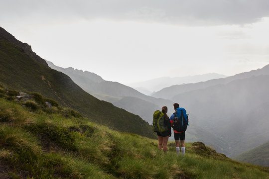 Young couple of backpackers enjoying the mountains and valleys on a rain summer day