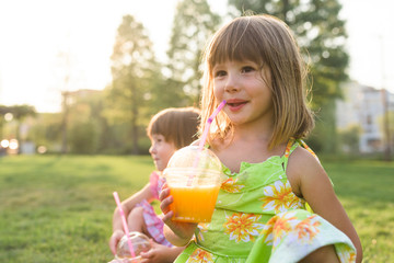 Portrait of young girl drinking orange juice outdoor in the park