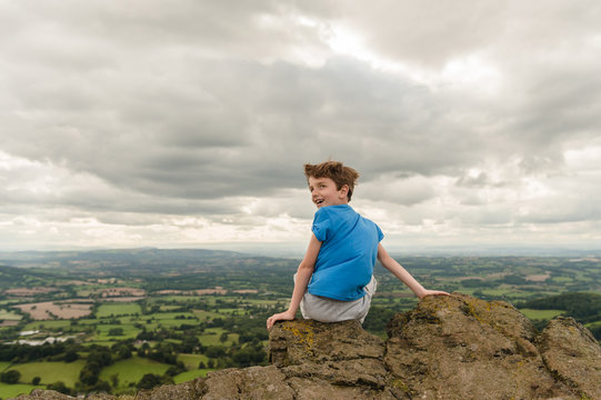 Tween boy sitting at the summit of a hill after his climb