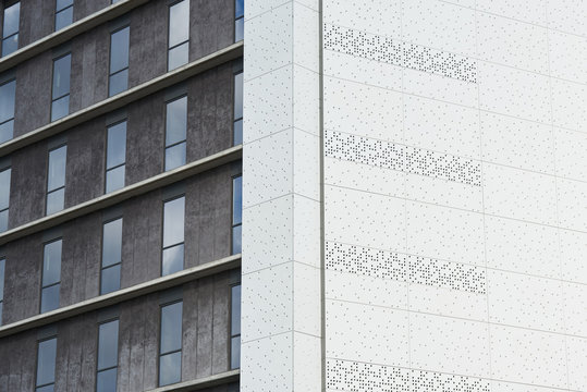 White textured building wall against grey block with windows.