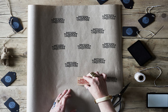 Woman making homemade Christmas gift wrap paper with ink stamp and brown paper.