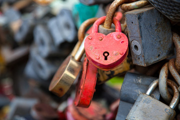 Close-up of the pink castle and other castles in the form of hearts on the old city bridge, the tradition of lovers on the wedding day