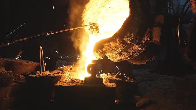 Operator pouring molten metal in automatic casting line in foundry factory, electric melting, high precision casting part manufacturing