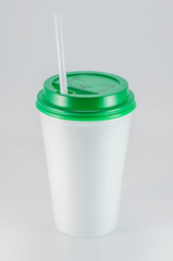 white plastic coffee cup with green lid on white background, view from above with copy space