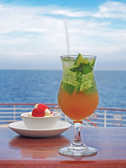 Mojito cocktail with lime and mint on a background of sea, sky with clouds. 