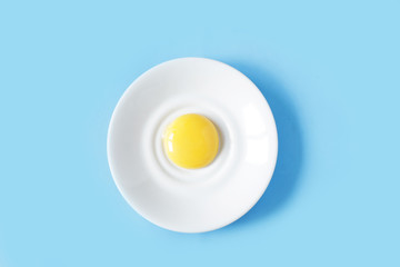 Yolk on a white plate on blue background  top view