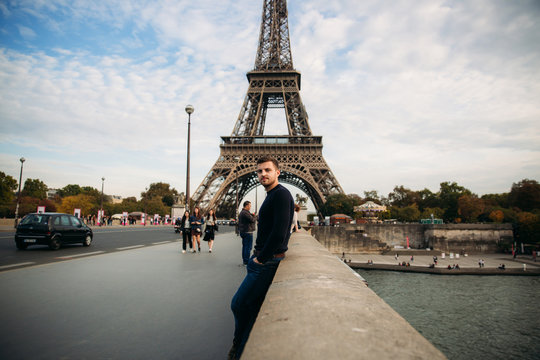 Handsome man in dark pullover is standing on the bridge background of the Eiffel Tower