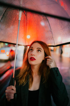 woman with a trasparent umbrella on a rainy ay with the city lights