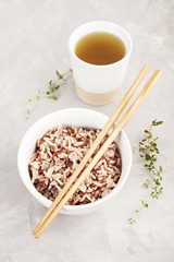 Assorted multi-colored wild rice in ceramic bowl and chopsticks with green tea. Black, brown and white rice...