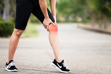 Asian woman runner holding her sports injured leg,exercise and healthy concept.