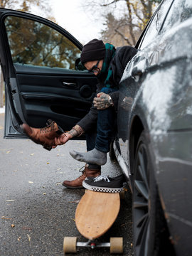 A man changes his footwear in anticipation of longboarding