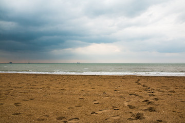 Dark sands with many footprints on the beach under low cloudy sky